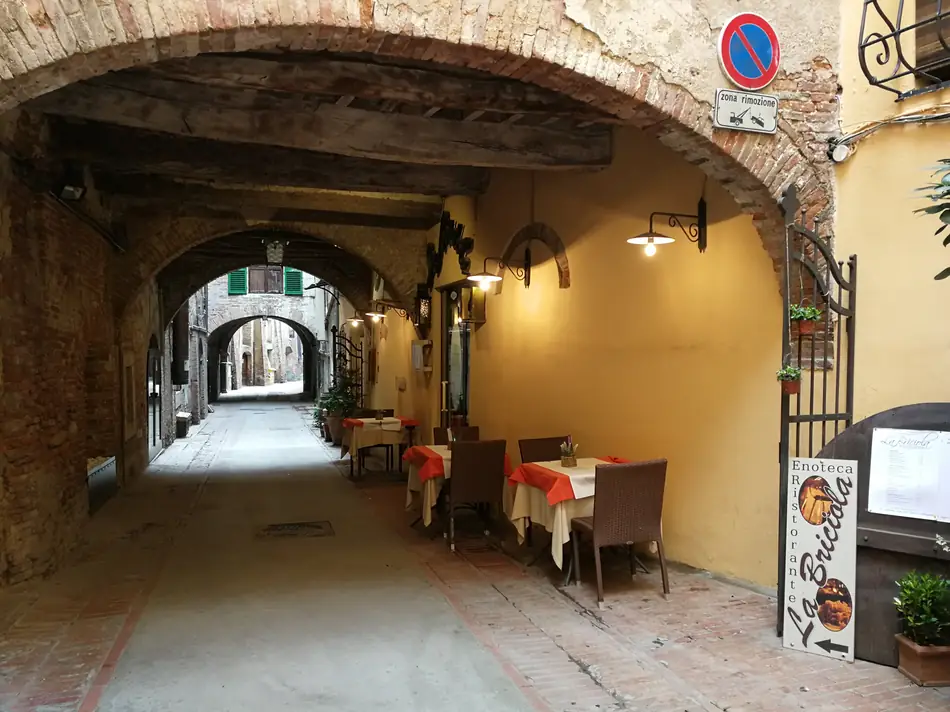 I tavoli all'aperto sotto l'arco di pietra della via