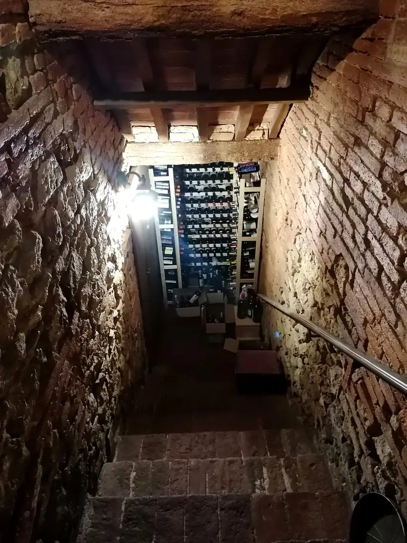 La scala di pietra che scende nella cantina, con le rastrelliere di bottiglie