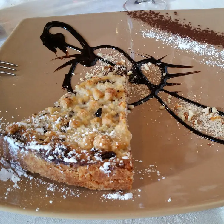 Una fetta di crostata di casa, zucchero a velo e decoro di cioccolato sul piatto