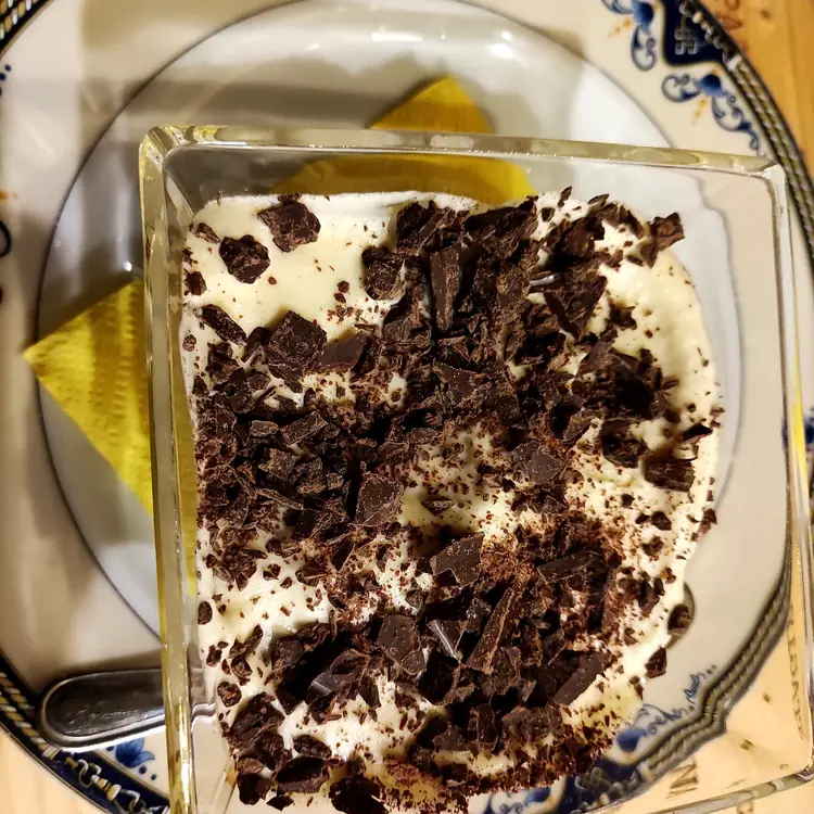 Tiramisù nel bicchiere di vetro, servito su piatto decorato