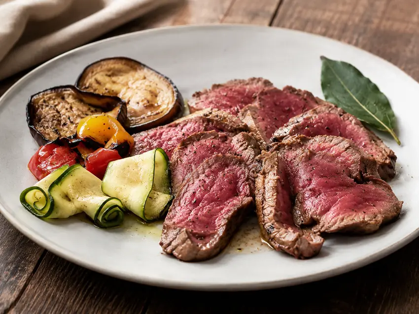 Tagliata di controfiletto affettata, servita con verdure grigliate
